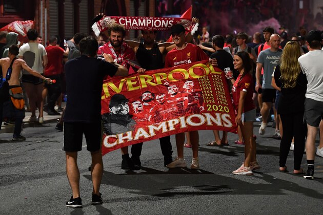 Fans celebrate Liverpool winning the Premier League title outside Anfield stadium in Liverpool, north west England on June 25, 2020, following Chelsea's 2-1 victory over Manchester City. - Liverpool were crowned Premier League champions without kicking a ball on Thursday as Chelsea's 2-1 win over Manchester City ended the Reds' 30-year wait to win the English title. Jurgen Klopp's men sealed a 19th league title for the club with a record seven games left to play after City's defeat left them 23 points adrift of Liverpool at the top. (Photo by Paul ELLIS / AFP) (Photo by PAUL ELLIS/AFP via Getty Images)