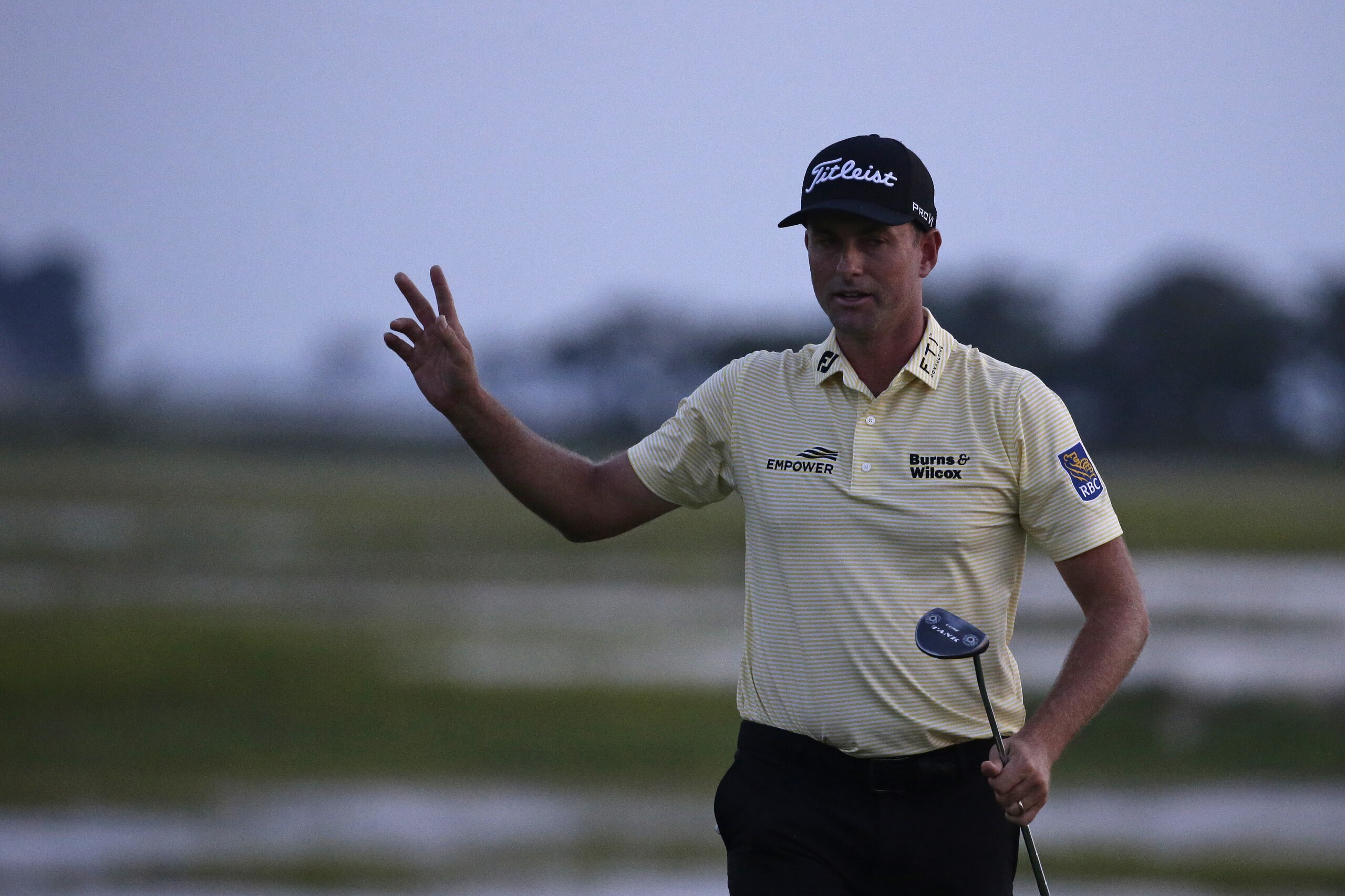Webb Simpson waves as the sun disappears on the 18th green, on a course with no fans due to the COVID-19 pandemic, during the final round of the RBC Heritage golf tournament, Sunday, June 21, 2020, in Hilton Head Island, S.C. (AP Photo/Gerry Broome)