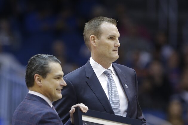 Orlando Magic CEO Alex Martins, left, presents former Magic player Pat Garrity with a painting to honor him during the first half of an NBA basketball game against the Detroit Pistons in Orlando, Fla., Friday, Dec. 27, 2013. Fomrer Magic players are being recognized through the 2013-2014 season on the 25th Anniversary of the team.(AP Photo/John Raoux)
