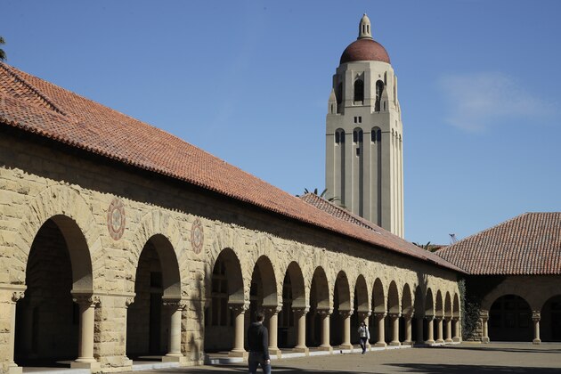 FILE- In this March 14, 2019, file photo, people walk on the Stanford University campus beneath Hoover Tower in Stanford, Calif. The amount of free money you receive for college may decrease after your freshman year. To hang on to scholarships and grants, and avoid paying more for your education than you expected, understand the terms of your financial aid offer, contact your school’s financial aid office if your income changes and plan ahead for tuition increases.(AP Photo/Ben Margot, File)