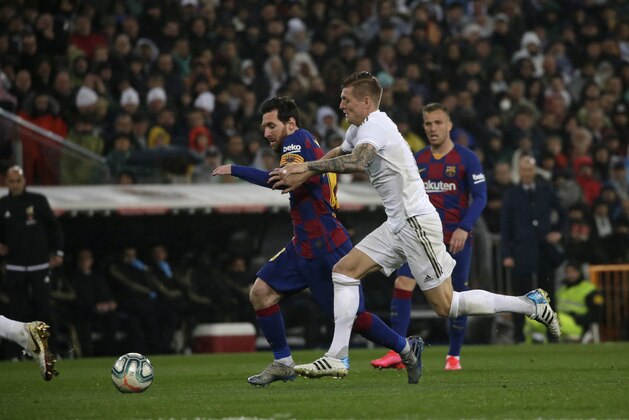 Barcelona's Lionel Messi is challenged by Real Madrid's Toni Kroos during the Spanish La Liga soccer match between Real Madrid and Barcelona at the Santiago Bernabeu stadium in Madrid, Spain, Sunday, March 1, 2020. (AP Photo/Andrea Comas)