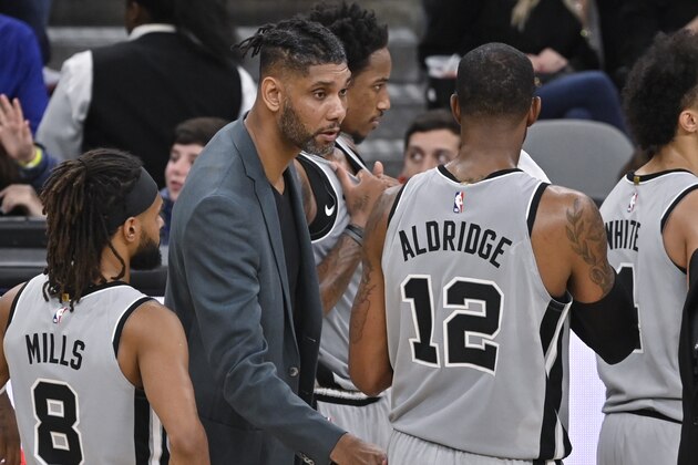 San Antonio Spurs acting head coach Tim Duncan, center, talks to Spurs forward LaMarcus Aldridge (12) as guard Patty Mills looks on during the second half of an NBA basketball game against the Portland Trail Blazers, Saturday, Nov. 16, 2019, in San Antonio. Portland won 121-116. Duncan became acting head coach after Spurs head coach Gregg Popovich was ejected after being called for two technical fouls. (AP Photo/Darren Abate)
