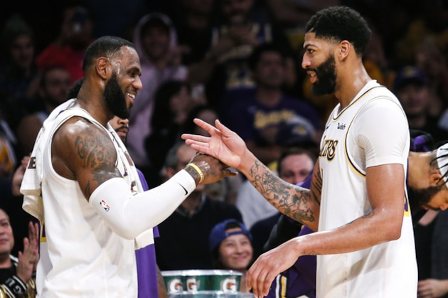 Los Angeles Lakers' LeBron James, left, celebrates with teammate Anthony Davis during a timeout in the second half of an NBA basketball game, Sunday, Dec. 8, 2019, in Los Angeles. The Lakers won 142-125. (AP Photo/Ringo H.W. Chiu)