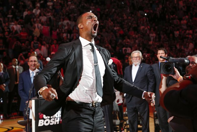Former Miami Heat player Chris Bosh reacts at the team's retirement of his jersey at halftime of an NBA game between the Heat and the Orlando Magic, Tuesday, March 26, 2019, in Miami. At right is Heat owner Micky Arison. Bosh played 13 seasons, the first seven in Toronto and the last six in Miami. He averaged 19.2 points and 8.5 rebounds, was an All-Star 11 times and won two championships.(AP Photo/Joe Skipper)