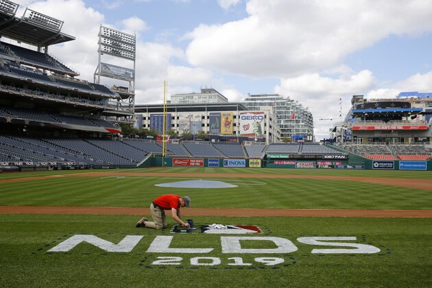 A groundskeeper paints a logo on the field at Nationals Park in Washington, Saturday, Oct. 5, 2019. Game 3 of the National League Division Series between the Los Angeles Dodgers and the Washington Nationals is scheduled to take place Sunday. (AP Photo/Patrick Semansky)