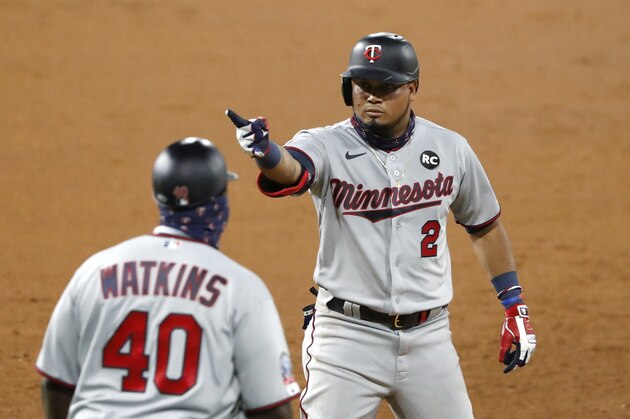 Minnesota Twins' Luis Arraez (2) acknowledges his teammates in the dugout after hitting a two-run single during the seventh inning of a baseball game against the Chicago White Sox, Friday, July 24, 2020, in Chicago. Watching Arraez react is first base coach Tommy Watkins. (AP Photo/Charles Rex Arbogast)