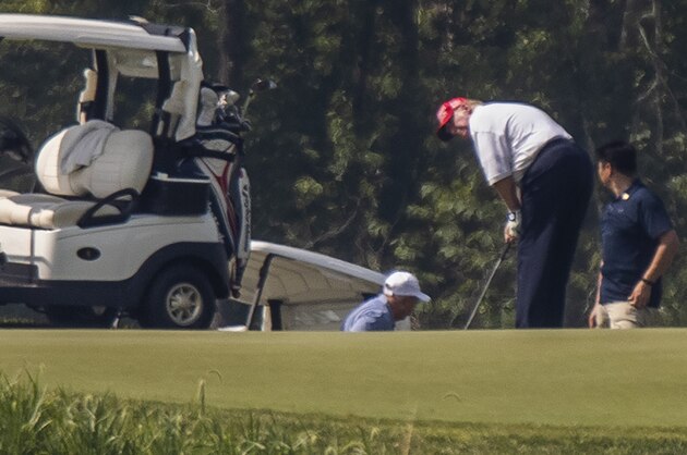 President Donald Trump and Sen. Lindsey Graham, R-S.C., back light blue shirt, play golf at Trump National Golf Club in Sterling, Va., as seen from the other side of the Potomac River in Darnestown, Md., Sunday, July 19, 2020. (AP Photo/Manuel Balce Ceneta)