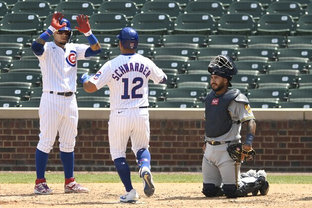 Chicago Cubs' Kyle Schwarber (12) celebrates with teammate Javier Baez left, while Milwaukee Brewers catcher Omar NarvÃ¡ez right, looks on at home plate after hitting a two-run home run during the fifth inning of a baseball game Saturday, July 25, 2020, in Chicago. (AP Photo/Paul Beaty)