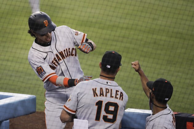 San Francisco Giants' Mauricio Dubon, left, is greeted by manager Gabe Kapler, center, and bench coach Kai Correa after scoring on a single by Darin Ruf during the third inning of the team's baseball game against the Los Angeles Dodgers, Sunday, July 26, 2020, in Los Angeles. (AP Photo/Jae C. Hong)