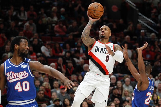 FILE - In this Saturday, March 7, 2020, file photo, Portland Trail Blazers guard Damian Lillard, center, shoots as Sacramento Kings forward Harrison Barnes, left, and forward Harry Giles III, right, defend during the first half of an NBA basketball game in Portland, Ore. Lillard says he will spend most of his downtime working on recording music while inside the NBA bubble. (AP Photo/Steve Dipaola, File)