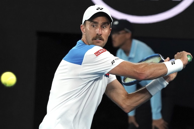 United States' Steve Johnson makes a backhand return to Switzerland's Roger Federer during their first round singles match at the Australian Open tennis championship in Melbourne, Australia, Monday, Jan. 20, 2020. (AP Photo/Lee Jin-man)
