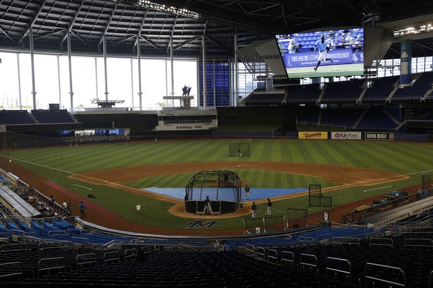 Baseball highlights play on the large screen as the Miami Marlins take batting practice during a baseball workout at Marlins Park, Sunday, July 5, 2020, in Miami. (AP Photo/Wilfredo Lee)