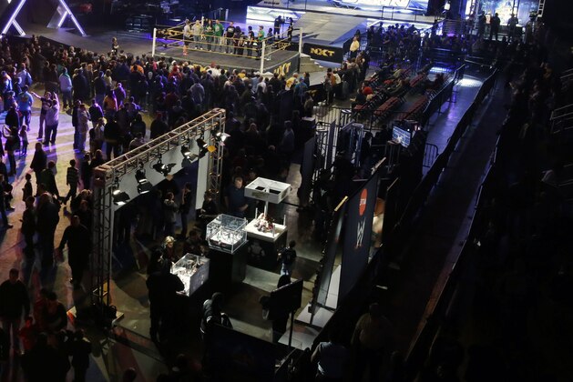 People walk around booths near a wresting ring at the Wrestlemania Axxess event, Saturday, April 6, 2013, in East Rutherford, N.J., ahead of Sunday's Wrestlemania at MetLife Stadium. (AP Photo/Mel Evans)