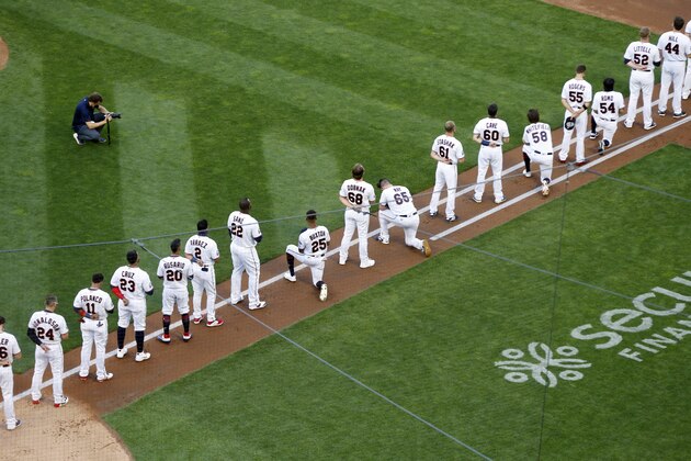 Minnesota Twins players stand during the national anthem while a few knelt down including Byron Buston (25) and Trevor May (65) prior to the Twins and St. Louis Cardinals baseball game Tuesday, July 28, 2020, in Minneapolis. (AP Photo/Jim Mone)