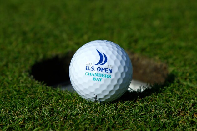 In this photo taken Sept. 30, 2014, a golf ball with one of the logos for Chambers Bay, the host course for the 2015 U.S. Open Championship, is shown next to a hole on the course in University Place, Wash. (AP Photo/Ted S. Warren)
