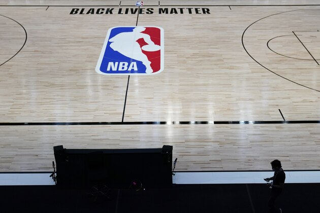 A man walks past a basketball court at ESPN Wide World of Sports Complex Wednesday, July 29, 2020, in Orlando, Fla. NBA games will resume Thursday. (AP Photo/Ashley Landis)