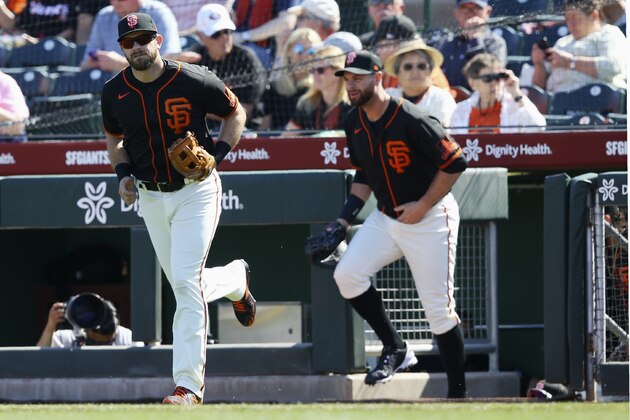 San Francisco Giants third baseman Evan Longoria, left, and Giants first baseman Brandon Belt, right, run onto the field prior to a spring training baseball game against the Arizona Diamondbacks Monday, Feb. 24, 2020, in Scottsdale, Ariz. The Giants defeated the Diamondbacks 11-9. (AP Photo/Ross D. Franklin)