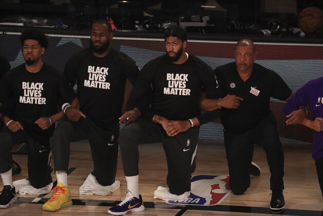 Los Angeles Lakers' LeBron James, second from left, wears a Black Lives Matter shirt and kneels with teammates during the national anthem prior to an NBA basketball game against the Los Angeles Clippers, Thursday, July 30, 2020, in Lake Buena Vista, Fla. (Mike Ehrmann/Getty Imagesvia AP, Pool)