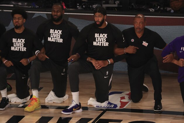 Los Angeles Lakers' LeBron James, second from left, wears a Black Lives Matter shirt and kneels with teammates during the national anthem prior to an NBA basketball game against the Los Angeles Clippers, Thursday, July 30, 2020, in Lake Buena Vista, Fla. (Mike Ehrmann/Pool Photo via AP)