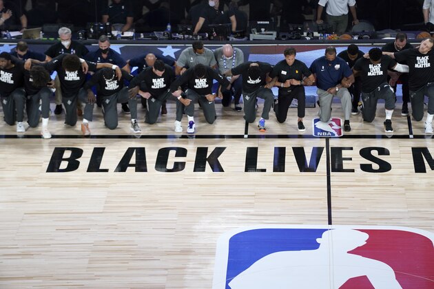 Members of the New Orleans Pelicans and Utah Jazz kneel together around the Black Lives Matter logo on the court during the national anthem before the start of an NBA basketball game Thursday, July 30, 2020, in Lake Buena Vista, Fla. (AP Photo/Ashley Landis, Pool)