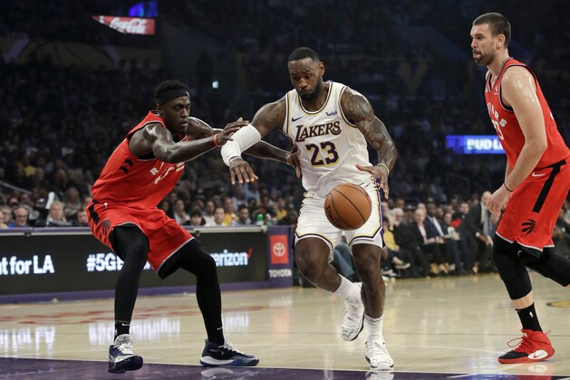 Los Angeles Lakers' LeBron James (23) dribbles between Toronto Raptors' Pascal Siakam, left, and Marc Gasol during the first half of an NBA basketball game Sunday, Nov. 10, 2019, in Los Angeles. (AP Photo/Marcio Jose Sanchez)