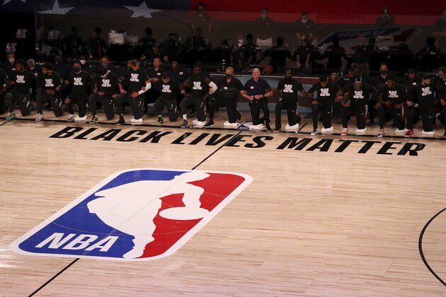 Players, coaches and staff kneel during the national anthem before an NBA basketball game between the Houston Rockets and the Dallas Mavericks  Friday, July 31, 2020, in Lake Buena Vista, Fla. (Mike Ehrmann/Pool Photo via AP)