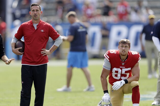 San Francisco 49ers head coach Kyle Shanahan, left, stands on the field as tight end George Kittle kneels prior to an NFL football game against the Los Angeles Chargers, Sunday, Sept. 30, 2018, in Carson, Calif. (AP Photo/Marcio Sanchez)
