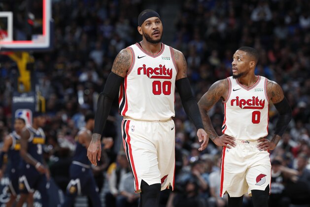Portland Trail Blazers forward Carmelo Anthony, left, and guard Damian Lillard head to the bench during a time out against the Denver Nuggets in the second half of an NBA basketball game Thursday, Dec. 12, 2019, in Denver. The Nuggets won 114-99. (AP Photo/David Zalubowski)