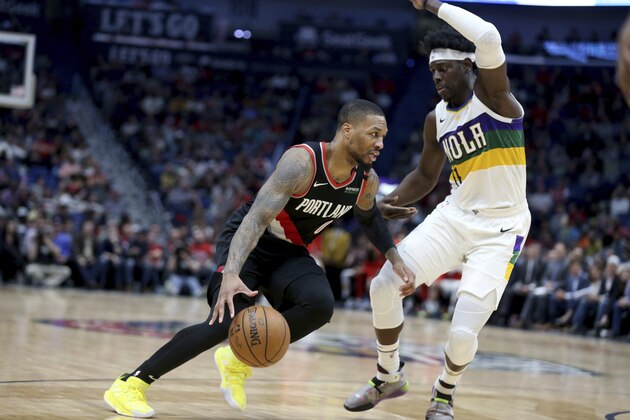 Portland Trail Blazers guard Damian Lillard (0) drives to the basket as New Orleans Pelicans guard Jrue Holiday (11) defends in the first half of an NBA basketball game in New Orleans, Tuesday, Feb. 11, 2020. (AP Photo/Rusty Costanza)