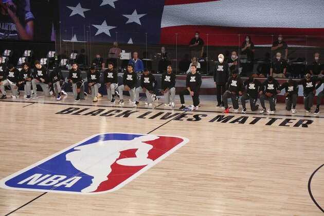 San Antonio Spurs head coach Gregg Popovich stands as other players and staff on the Spurs and the Sacramento Kings kneel around a Black Lives Matters logo on the court before an NBA basketball game, Friday, July 31, 2020, in Lake Buena Vista, Fla. (Kim Klement/Pool Photo via AP)