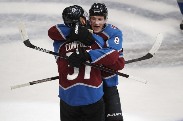 Colorado Avalanche defenseman Cale Makar, back, hugs left wing J.T. Compher, who scored in overtime of the team's NHL hockey game against the New York Rangers on Wednesday, March 11, 2020, in Denver. Colorado won 3-2. (AP Photo/David Zalubowski)