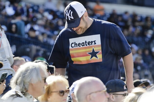 A New York Yankees fan, wearing a T-shirt mocking the Houston Astros, takes his seat during the sixth inning of a spring training baseball game against the Detroit Tigers, Saturday, Feb. 29, 2020, in Tampa, Fla. (AP Photo/Frank Franklin II)