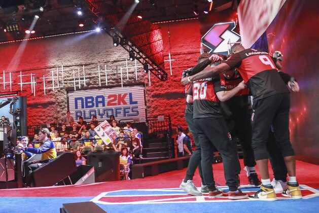 Team members of Blazers Gaming, an NBA 2k League (NBA2KL) professional esports team, huddle before taking seats at their video stations for a match against Warriors Gaming Squad, Wednesday, July 24, 2019, in Queens borough of New York. The teams kicked off day one of the NBA2KL playoffs with Blazers on the losing 67-45. (AP Photo/Bebeto Matthews)