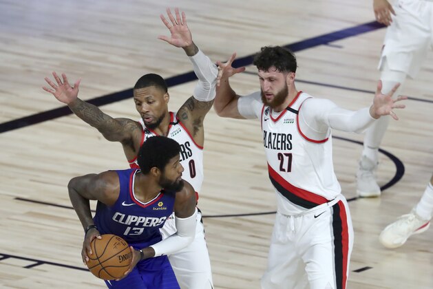 Los Angeles Clippers guard Paul George (13) looks to pass as Portland Trail Blazers guard Damian Lillard (0) and center Jusuf Nurkic (27) defend during the second half in an NBA basketball game Saturday, Aug. 8, 2020, in Lake Buena Vista, Fla. (Kim Klement/Pool Photo via AP)
