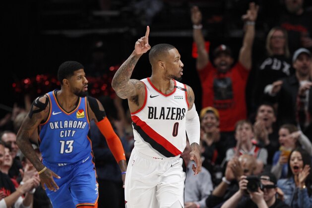Portland Trail Blazers guard Damian Lillard, right, reacts after making a basket as Oklahoma City Thunder forward Paul George, left, trails the play during the first half of Game 1 of a first-round NBA basketball playoff series in Portland, Ore., Sunday, April 14, 2019. (AP Photo/Steve Dipaola)