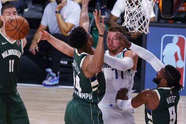Dallas Mavericks' Luka Doncic passes away from Milwaukee Bucks' Giannis Antetokounmpo (34) and Wesley Matthews, right, during an NBA basketball game Saturday, Aug. 8, 2020, in Lake Buena Vista, Fla. (Kevin C. Cox/Pool Photo via AP)