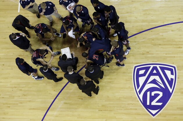 Arizona head coach Sean Miller, center-left, with clipboard, talks to his team as they gather near the Pac-12 logo on the court prior to the start of a Pac-12 NCAA college basketball game against Washington, Thursday, Jan. 31, 2013, in Seattle. (AP Photo/Ted S. Warren)