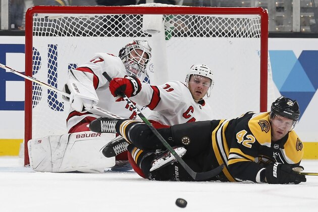 Carolina Hurricanes' James Reimer (47) and Lucas Wallmark (71) and Boston Bruins' David Backes (42) watch as the puck clears from in front of the net during the third period of an NHL hockey game in Boston, Tuesday, Dec. 3, 2019. (AP Photo/Michael Dwyer)