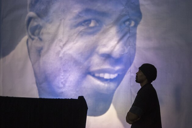 A man is framed by a giant poster of Jackie Robinson as he watches the ceremonial ground breaking for the Jackie Robinson Museum, Thursday, April 27, 2017, in New York. (AP Photo/Mary Altaffer)