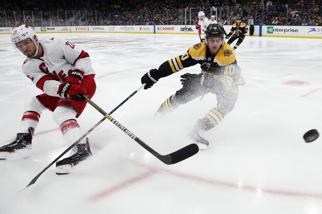 Carolina Hurricanes' Brett Pesce (22) sends the puck past Boston Bruins' Anders Bjork (10) during the first period of an NHL hockey game in Boston, Tuesday, Dec. 3, 2019. (AP Photo/Michael Dwyer)