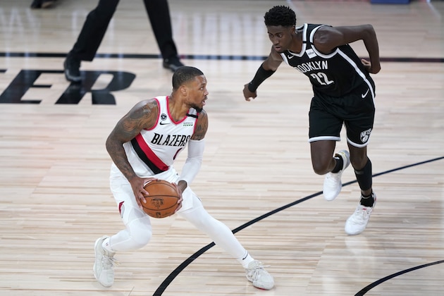 Portland Trail Blazers' Damian Lillard, left, works the floor against Brooklyn Nets' Caris LeVert during the first half of an NBA basketball game Thursday, Aug. 13, 2020 in Lake Buena Vista, Fla. (AP Photo/Ashley Landis, Pool)