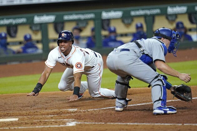 Houston Astros' Michael Brantley, left, scores as Los Angeles Dodgers catcher Will Smith waits for the throw during the fourth inning of a baseball game Tuesday, July 28, 2020, in Houston. (AP Photo/David J. Phillip)