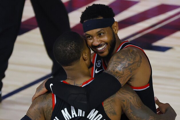 Portland Trail Blazers' Carmelo Anthony hugs Damian Lillard (0) after defeating the Memphis Grizzlies in an NBA basketball game Saturday, Aug. 15, 2020, in Lake Buena Vista, Fla. (Kevin C. Cox/Pool Photo via AP)