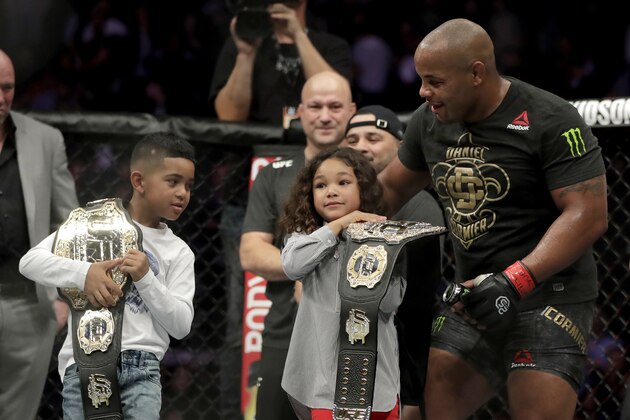 Daniel Cormier, right, lets his kids, Daniel, left, and Marquita, hold his championship belts after he defeated Derrick Lewis by submission in the second round of a heavyweight mixed martial arts bout at UFC 230, early Sunday, Nov. 4, 2018, at Madison Square Garden in New York. (AP Photo/Julio Cortez)