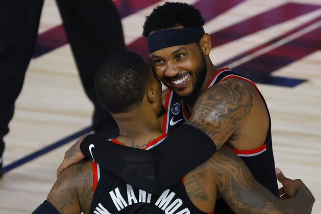 Portland Trail Blazers' Carmelo Anthony hugs Damian Lillard (0) after defeating the Memphis Grizzlies in an NBA basketball game Saturday, Aug. 15, 2020, in Lake Buena Vista, Fla. (Kevin C. Cox/Pool Photo via AP)