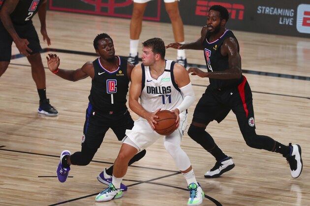 Dallas Mavericks guard Tim Hardaway Jr. is defended by Los Angeles Clippers guard Reggie Jackson (1) and forward JaMychal Green (4) during the second half of Game 1 of an NBA basketball first-round playoff series, Monday, Aug. 17, 2020, in Lake Buena Vista, Fla. (Kim Klement/Pool Photo via AP)