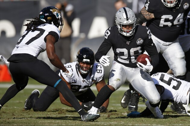 Oakland Raiders running back Josh Jacobs runs with the ball past Jacksonville Jaguars cornerback Tre Herndon (37) and Calais Campbell (93) during the first half of an NFL football game in Oakland, Calif., Sunday, Dec. 15, 2019. (AP Photo/D. Ross Cameron)