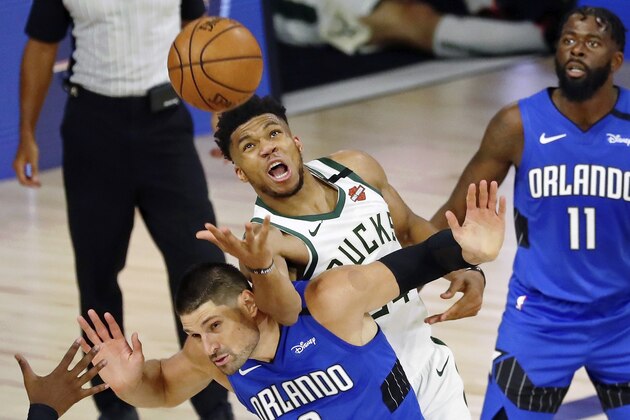 Milwaukee Bucks forward Giannis Antetokounmpo (34) fouls Orlando Magic center Nikola Vucevic (9) while reaching for a loose ball during the second half of Game 1 of an NBA basketball first-round playoff series, Tuesday, Aug. 18, 2020, in Lake Buena Vista, Fla. (Kim Klement/Pool Photo via AP)