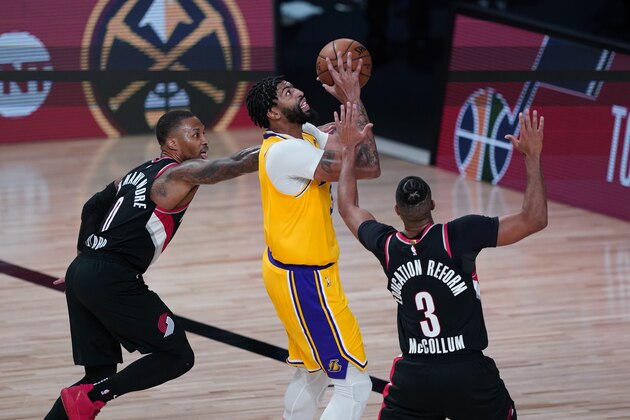 Los Angeles Lakers forward Anthony Davis goes to the basket between Portland Trail Blazers guard Damian Lillard (0) and guard CJ McCollum (3) during the second half of an NBA basketball game Tuesday, Aug. 18, 2020, in Lake Buena Vista, Fla. (AP Photo/Ashley Landis, Pool)
