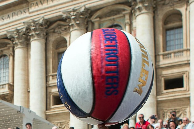 Harlem Globetrotters' Hi-Lite Bruton, second from left, Ant Atkinson, third from left,  look at teammate Flight Time Lang, right, helping Pope Francis spin the ball on his finger as they meet during the general audience in St. Peter's Square at the Vatican, Wednesday, May 6, 2015. (L'Osservatore Romano/Pool Photo via AP)